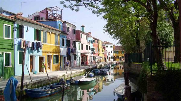 Colorful houses along Burano canal, moored boats, laundry drying in sunlight