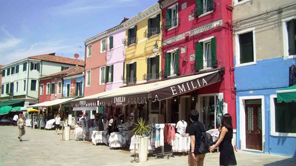 Colorful houses and lace market stalls under awnings, tourists strolling in Burano