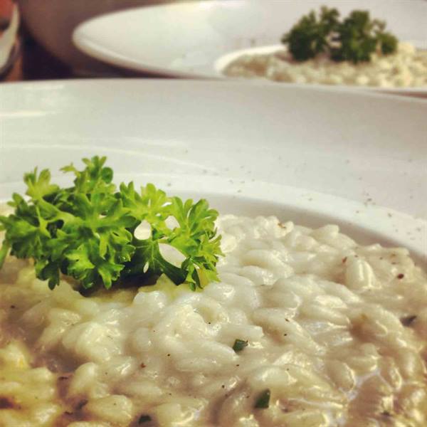 Creamy risotto in white plates, garnished with fresh parsley