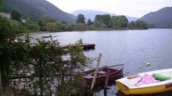 Yellow and brown wooden boats moored on a lake surrounded by green mountains