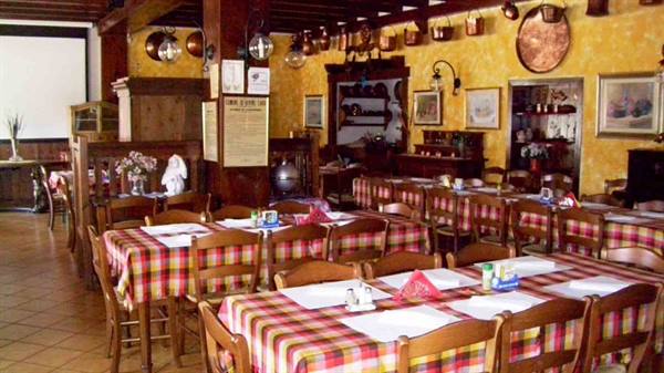 Trattoria dining room with tables set in checkered cloths and copper pots hanging