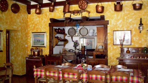 Rustic dining room with hanging copper pots, checkered tablecloth and wooden furniture