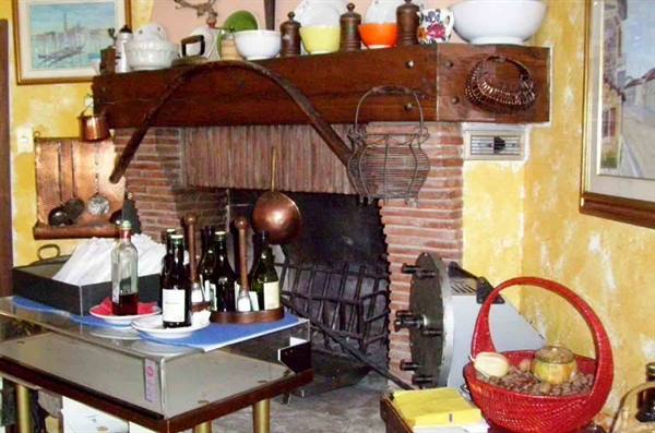 Brick fireplace with copper pots and wine bottles in a trattoria