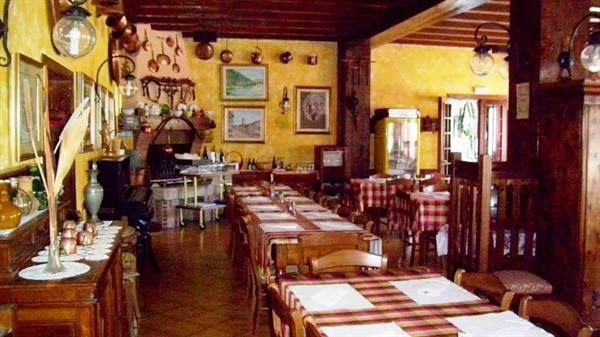 Trattoria dining room with set tables, checkered tablecloths, yellow walls and copper pots