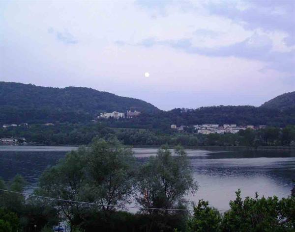 Moon over Lake Paola surrounded by wooded hills at dusk