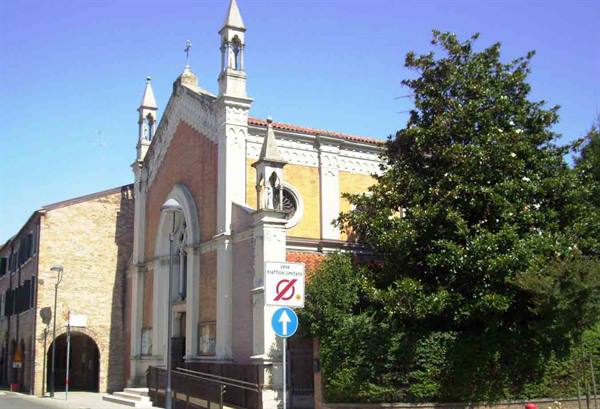 Church with brick facade and white spires, street signs and green tree