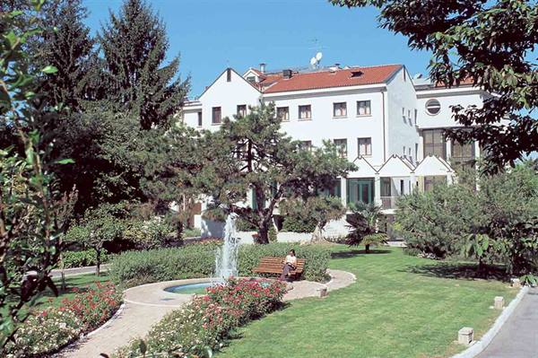 Person sitting on a bench by the fountain, in the garden of a hotel