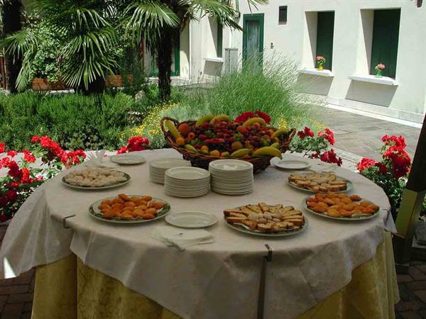 Table set with pastries and fruit in a sunny courtyard with red flowers