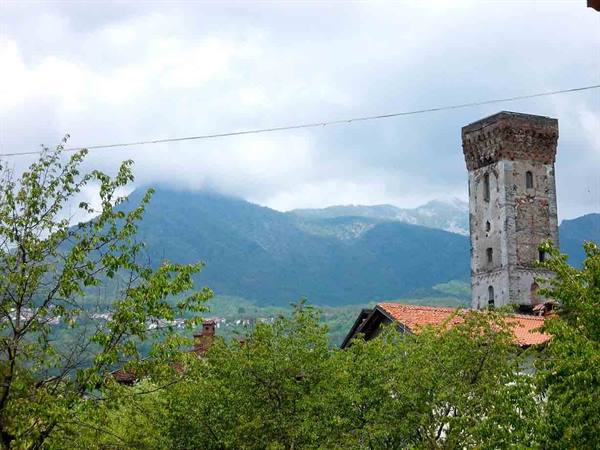 Ancient stone tower above red-tiled roofs, mountains wrapped in clouds