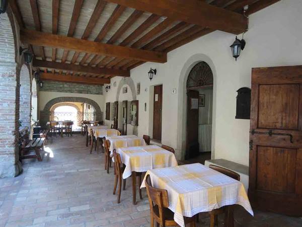 Wooden-beamed porch with tables set with yellow checkered tablecloths