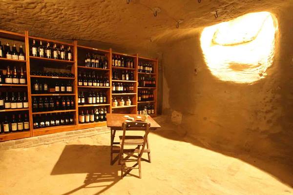 Wine cellar carved in rock, bottle shelves, wooden table