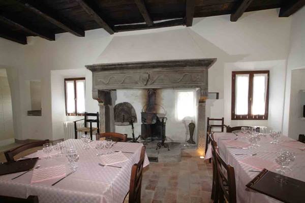 Dining room with set tables and old stone fireplace between windows
