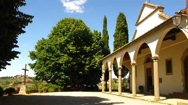 White church with arched columned portico, cypresses and wooden cross