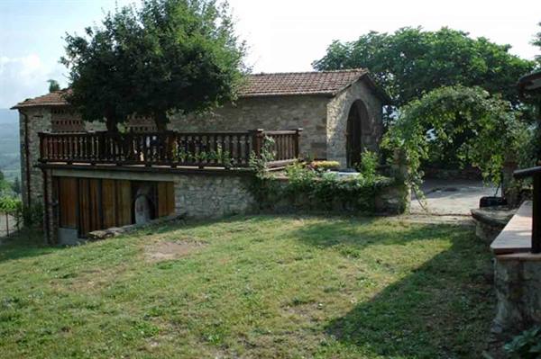 Stone farmhouse with wooden terrace and green lawn in front