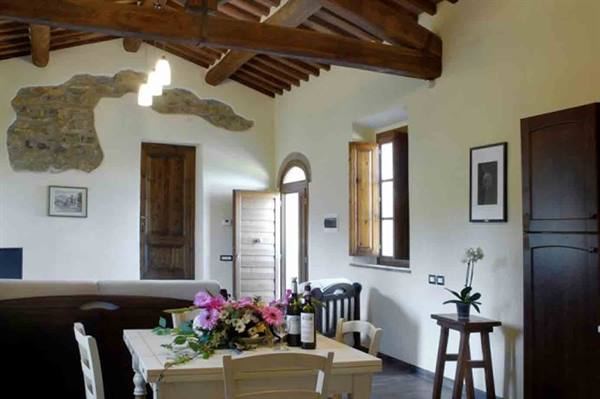 Rustic dining room with wooden beams, exposed stone, flowers and wine on table