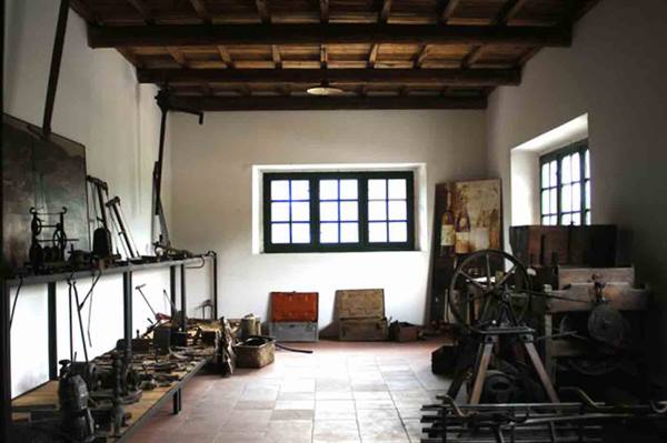 Old workshop with iron tools, whitewashed walls, wooden beams and windows