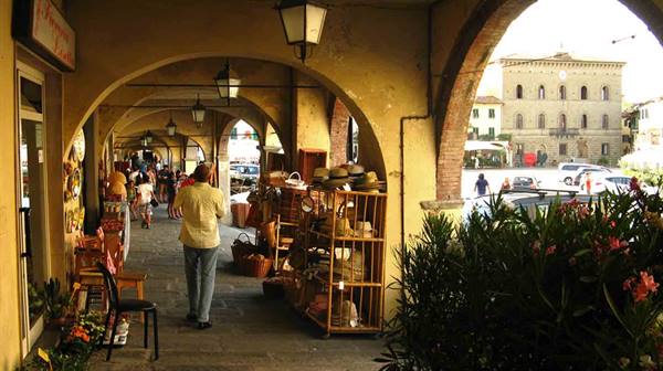 Brick arcades with wicker basket shops along a Tuscan square, Greve in Chianti