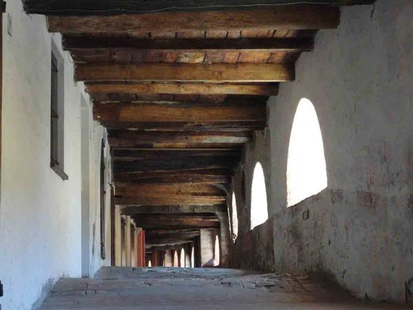 Wooden-beamed loggia with arched skylights lighting the stone floor