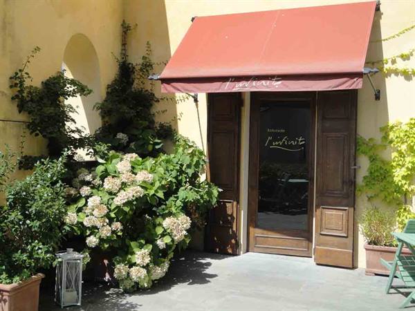 Restaurant entrance with red awning, white hydrangeas and sunny yellow wall
