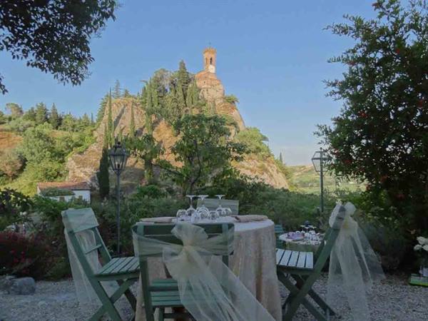 Garden table set with tulle bows, behind the hilltop clock tower of Brisighella
