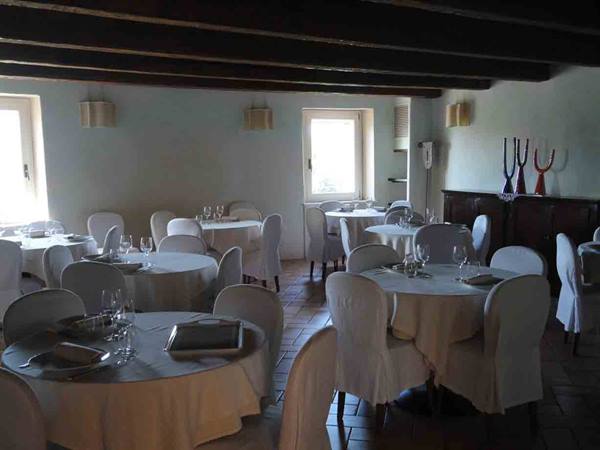 Restaurant dining room with white tablecloth tables set and wooden beamed ceiling