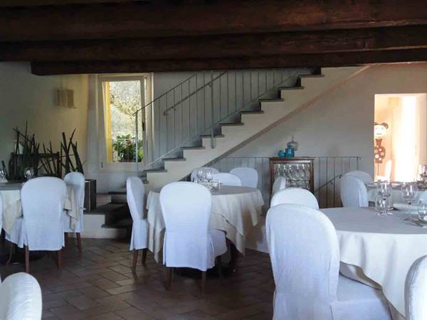Restaurant dining room with set tables, white slipcovered chairs and indoor staircase
