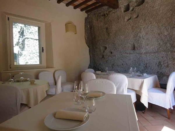 Restaurant dining room with white tablecloths and tufa rock wall