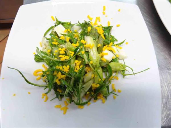 Green salad with crumbled egg on a white square plate