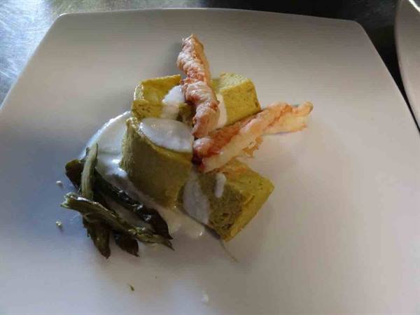 White plate with savory flan, fried shrimp and cream, kitchen light