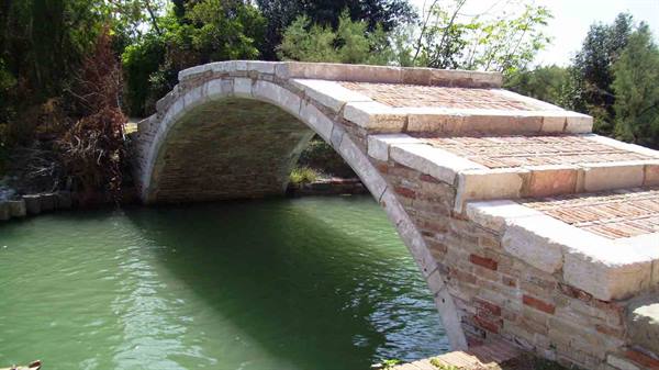 Devil's Bridge in Torcello: stone and brick arch over green canal