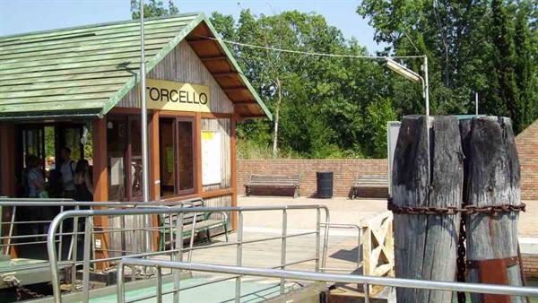 Torcello vaporetto stop: wooden kiosk with green roof, mooring poles and passengers