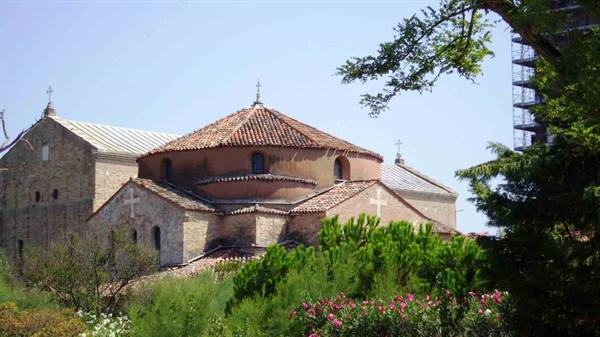 Torcello: the brick rotunda of Santa Fosca among trees and pink flowers
