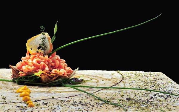 Shrimp garnished with herbs and crouton, served on a light stone slab