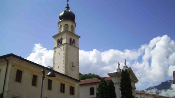 Bell tower with dome and clock beside white church under clouds