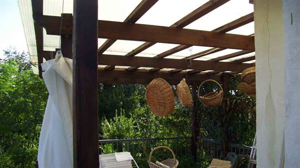 Wicker baskets hanging under a wooden pergola with transparent roof