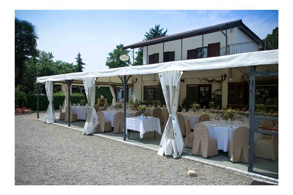 White tent with set tables and covered chairs in front of a villa