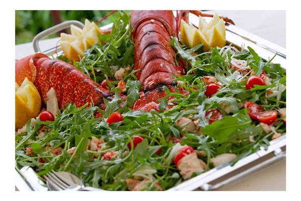 Silver tray with arugula salad, cherry tomatoes and lobster tails