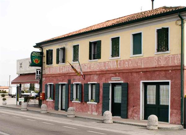 Old trattoria with vintage painted sign and banners along the road