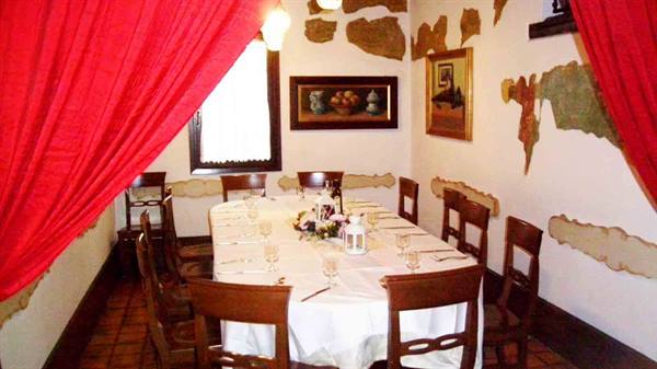 Restaurant dining room with set table, white tablecloth, wooden chairs and red drapes