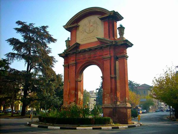 Arco del Meloncello in Bologna, red brick arch among trees and traffic