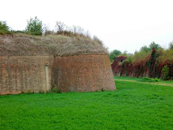 Brick bastion with grassy rampart, Renaissance walls under grey sky