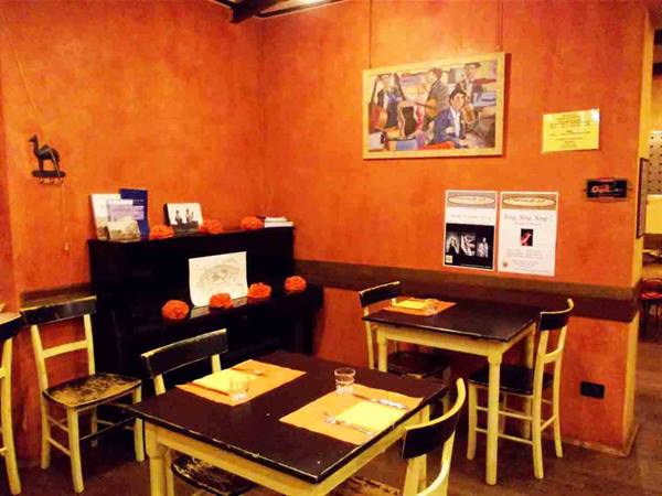 Set tables and a black piano inside the orange-walled dining room