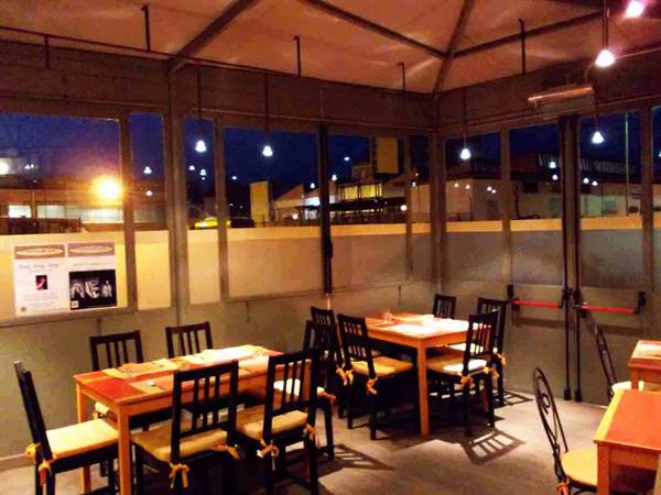 Wooden tables and chairs inside an illuminated eatery at night