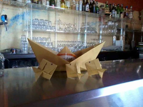 Kraft paper origami boat and frogs on the bar counter, glasses on the shelf