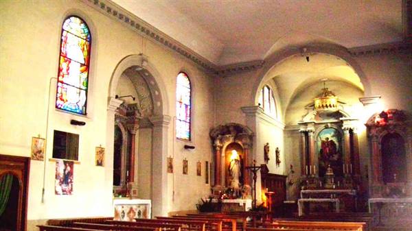 Church interior with colorful stained glass windows, ornate altar and wooden pews