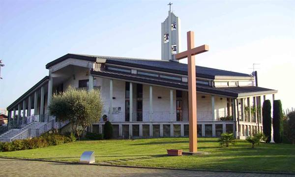 Modern church with bell tower and large wooden cross on the lawn