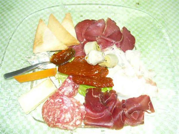 Glass plate with salami, ham, cheeses, peppers and toasted bread