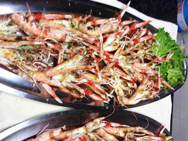 Metal trays full of herb-covered langoustines with celery leaves