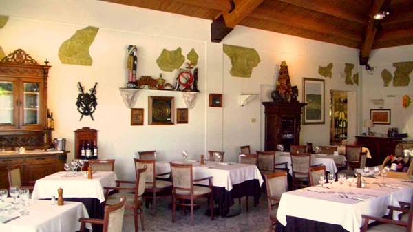 Restaurant dining room with white-clothed tables, antique furniture and wooden beams