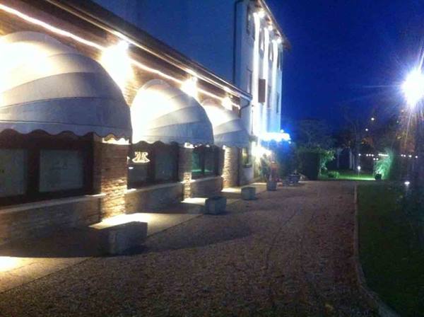 Restaurant facade at night with awnings and lights on brickwork